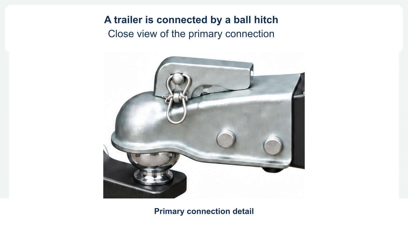 A neutral close view shows the trailer’s ball coupler and retaining pin. The wider connection area is outside this view. No safety chains, chain instruction or weight comparison is shown.